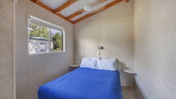 A bedroom with a bed, a window, and a ceiling fan.
