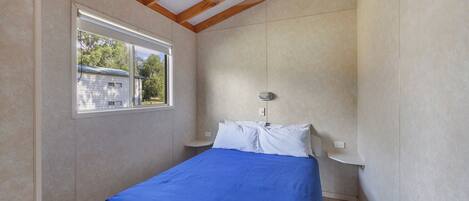 Un dormitorio con cama, ventana y ventilador de techo.