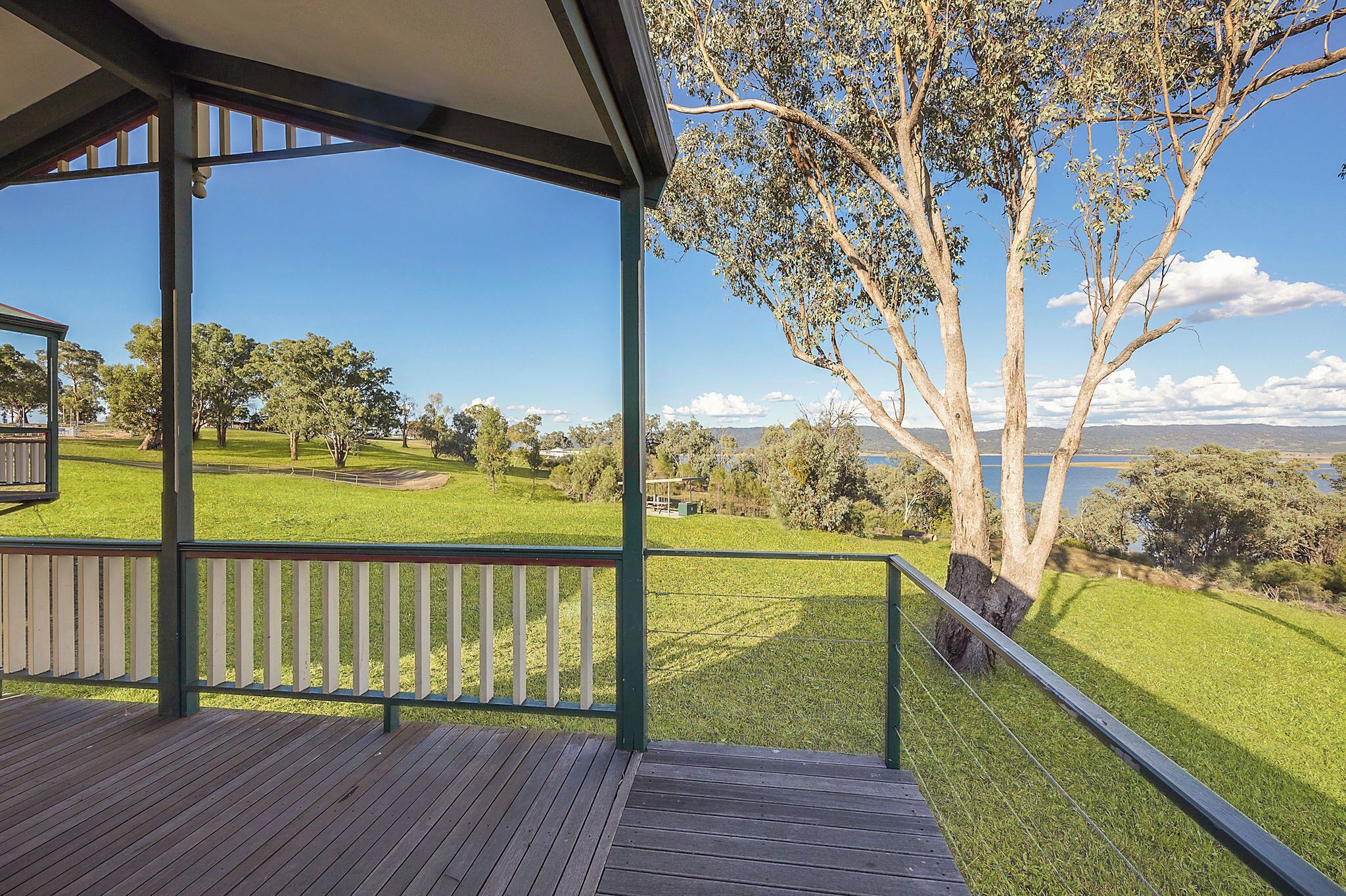 Eine Holzterrasse mit Blick auf einen Golfplatz und einen großen Baum.