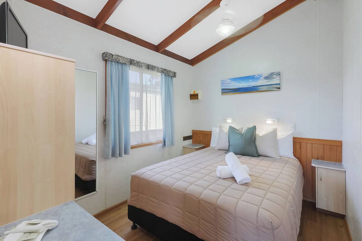 Ein Schlafzimmer mit Bett, Nachttischen, einem Kleiderschrank, einem Spiegel und einem Bild an der Wand.