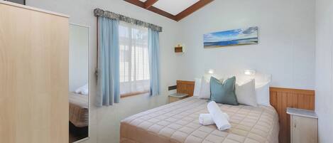 A bedroom with a bed, bedside tables, a wardrobe, a mirror, and a painting on the wall.