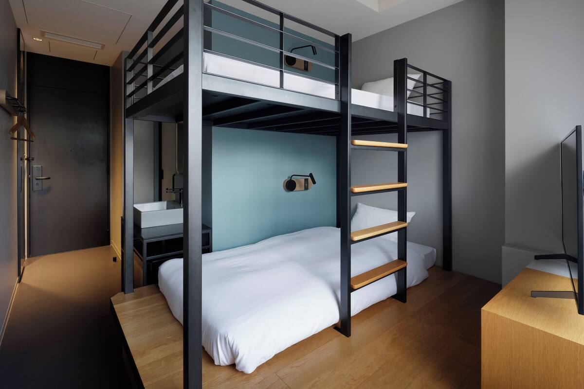 A bunk bed room with a desk and a TV.