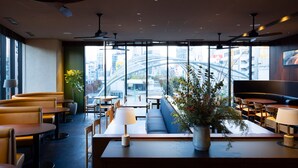 A modern restaurant with high ceilings, large windows, and a view of the cityscape. - sequence MIYASHITA PARK (Tokyo)