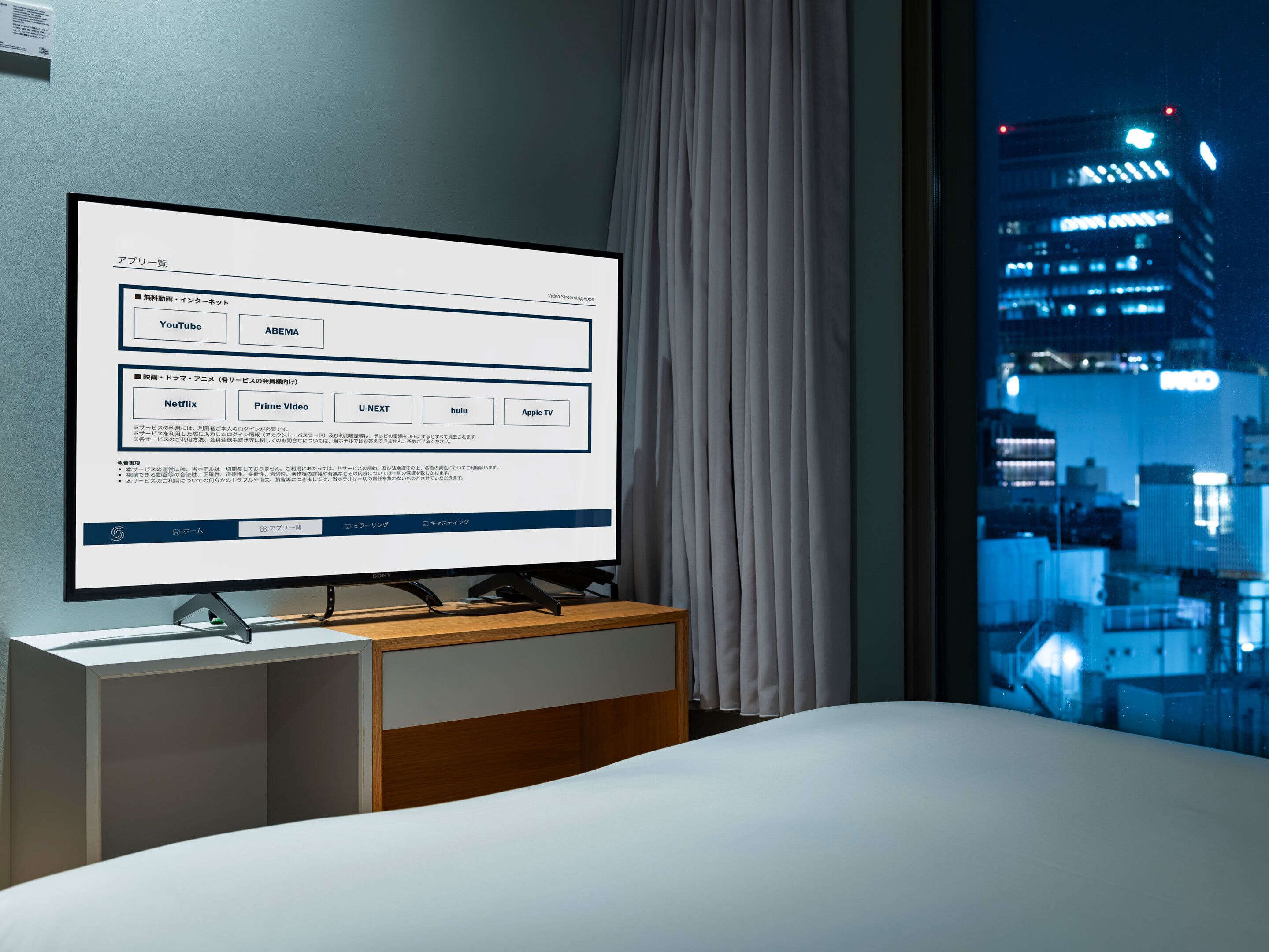 A hotel room with a large flat-screen TV displaying a video streaming app interface.