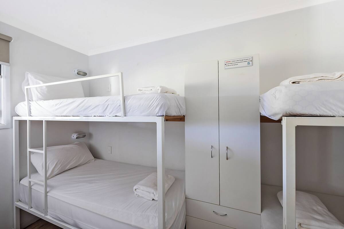 A bunk bed room with a wardrobe and a window.