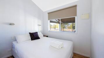 Een slaapkamer met een groot bed, een raam met uitzicht en een plafondlamp.