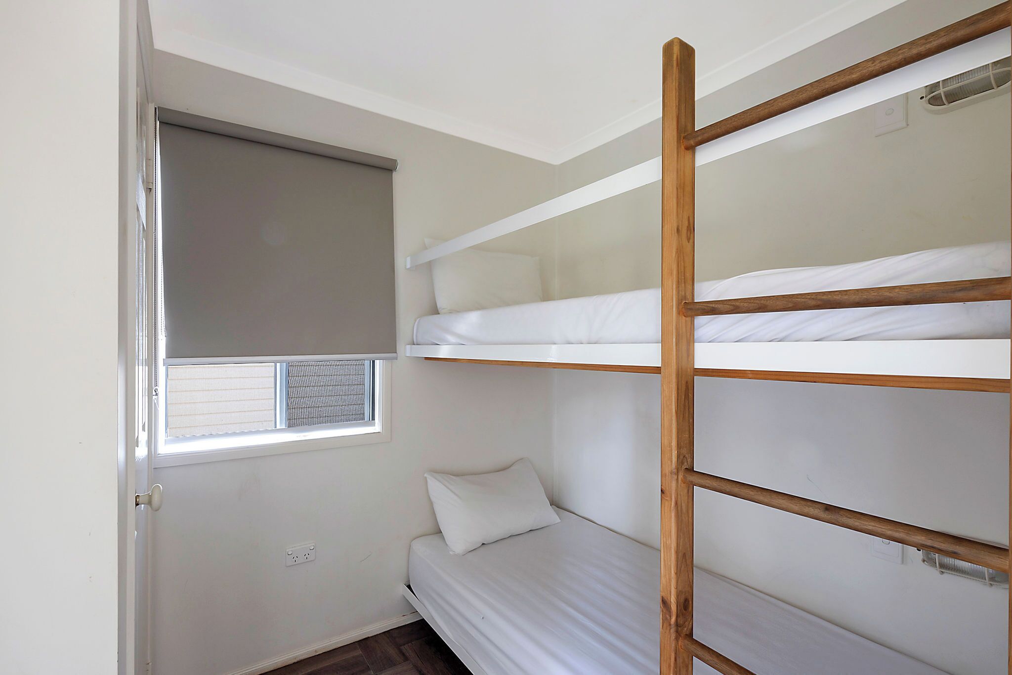 A compact room with bunk beds, a window with a blind, and a door.