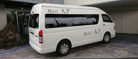 A white van parked in front of a building with a sign reading "Hotel A.P."