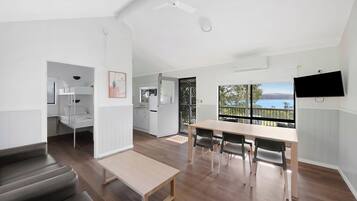 A modern, open-plan living space with a dining area, kitchen, and a balcony with a view.