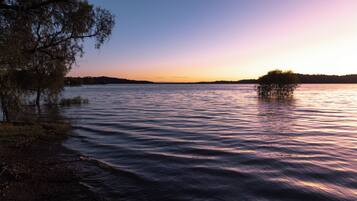 A calm lake at sunset with a small island in the center.