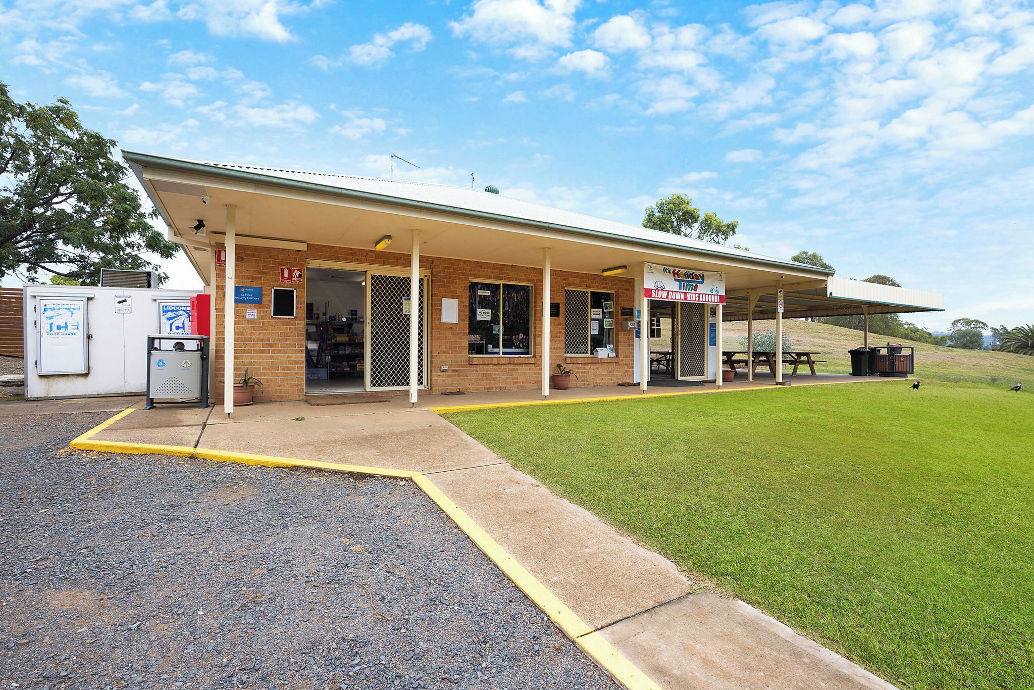 A building with a covered entrance, a signboard, and a picnic table outside.