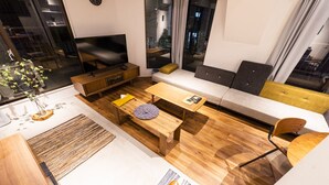 A modern living room with a sofa, coffee table, and TV. - Satellite Hotel Komagome (Tokyo)