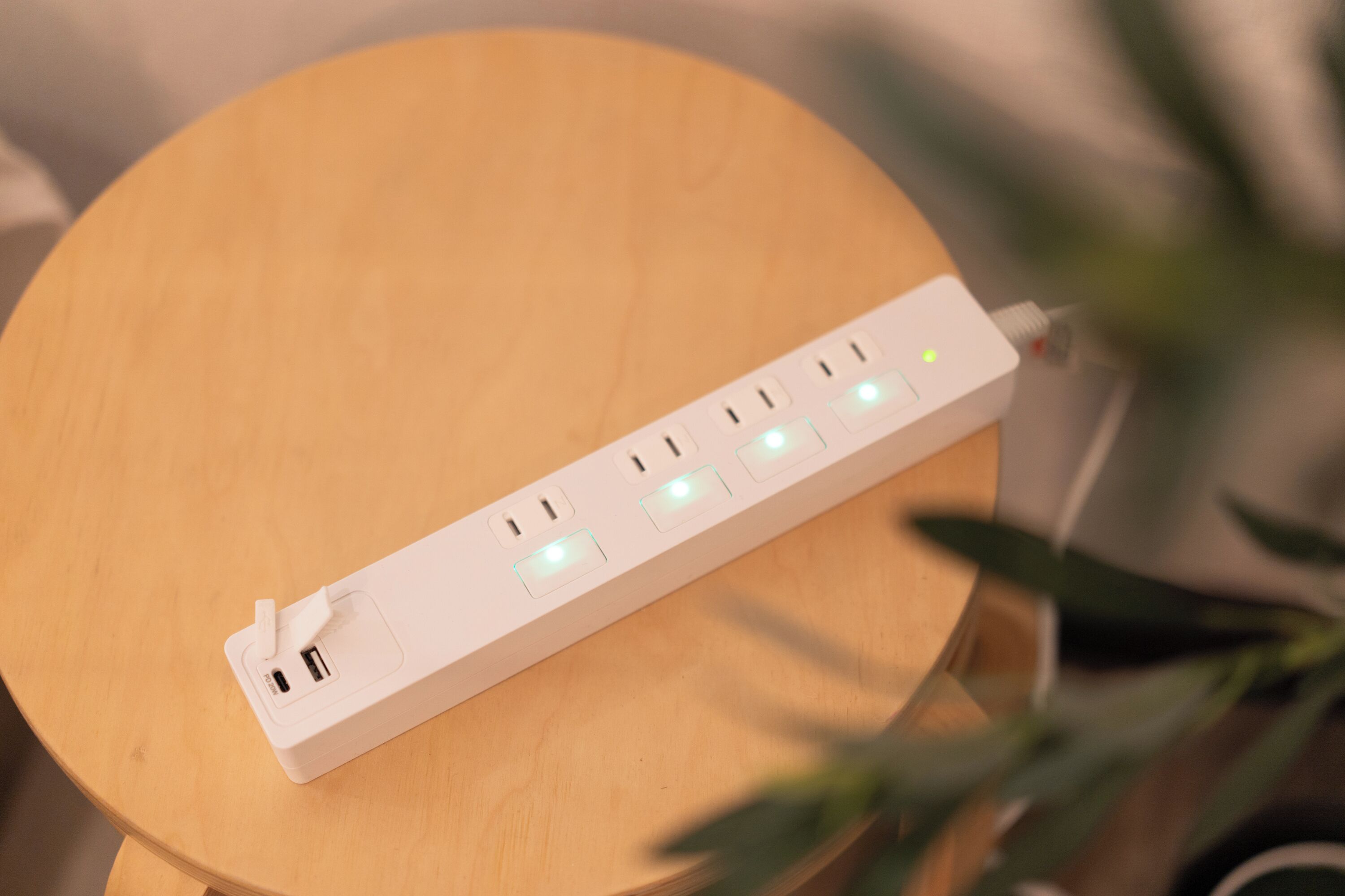 Una regleta blanca con múltiples enchufes y puertos USB sobre una superficie de madera.