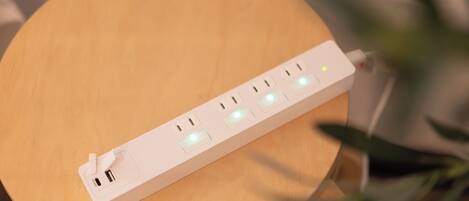 Una regleta blanca con múltiples enchufes y puertos USB sobre una superficie de madera.