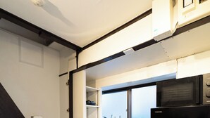 A kitchen with a black refrigerator, a stove, and a microwave. There is a window above the counter. - Satellite Hotel Yoyogi Sangubashi (Tokyo)