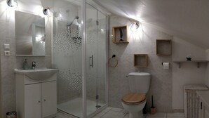 A modern bathroom with a glass-enclosed shower, a wooden toilet seat, a white sink, and a large mirror. - Gîte "U Caseddu (Ortiporio)