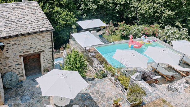 A stone building with a pool area, including umbrellas and lounge chairs. - Gîte "U Caseddu (Ortiporio)