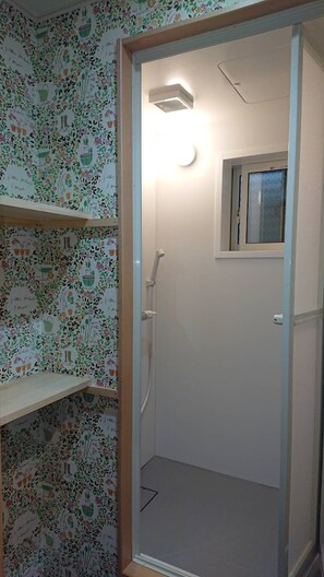 Un baño con ducha, una ventana y una puerta con panel de vidrio esmerilado.