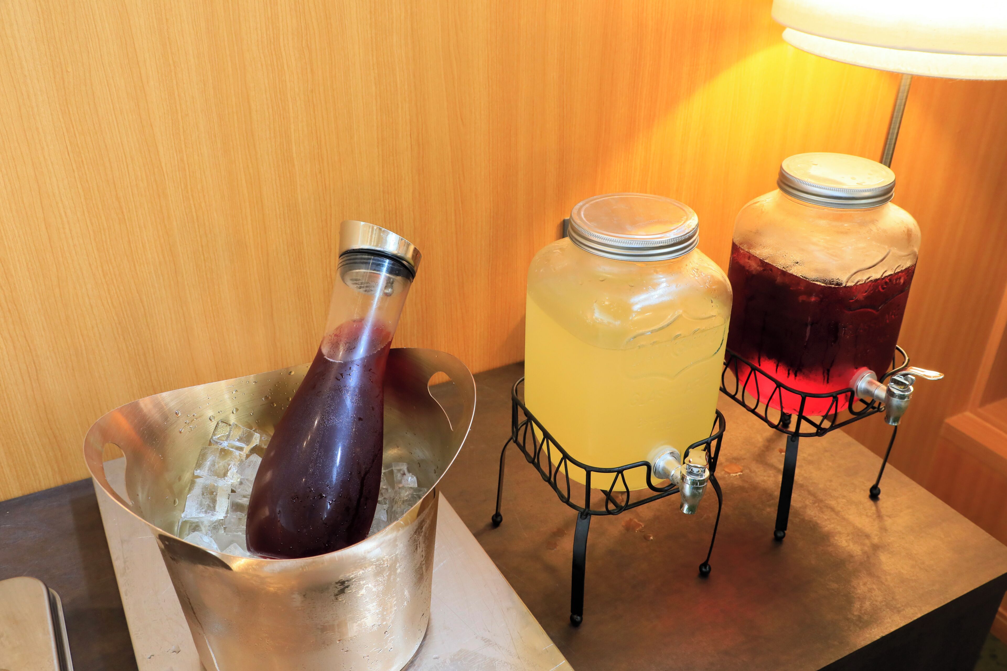 A beverage dispenser with two large containers and a smaller bottle, all placed on a metal stand.