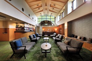 A lobby with a high ceiling, green carpet, and seating areas with tables. - YUTORELO NIKKO - Hostel (Nikko)