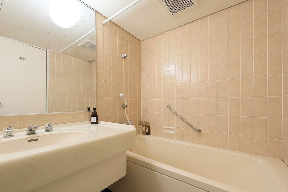 A bathroom with a sink, mirror, and bathtub.