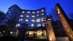 A multi-story hotel with illuminated windows and a prominent entrance sign. - YUTORELO NIKKO - Hostel (Nikko)