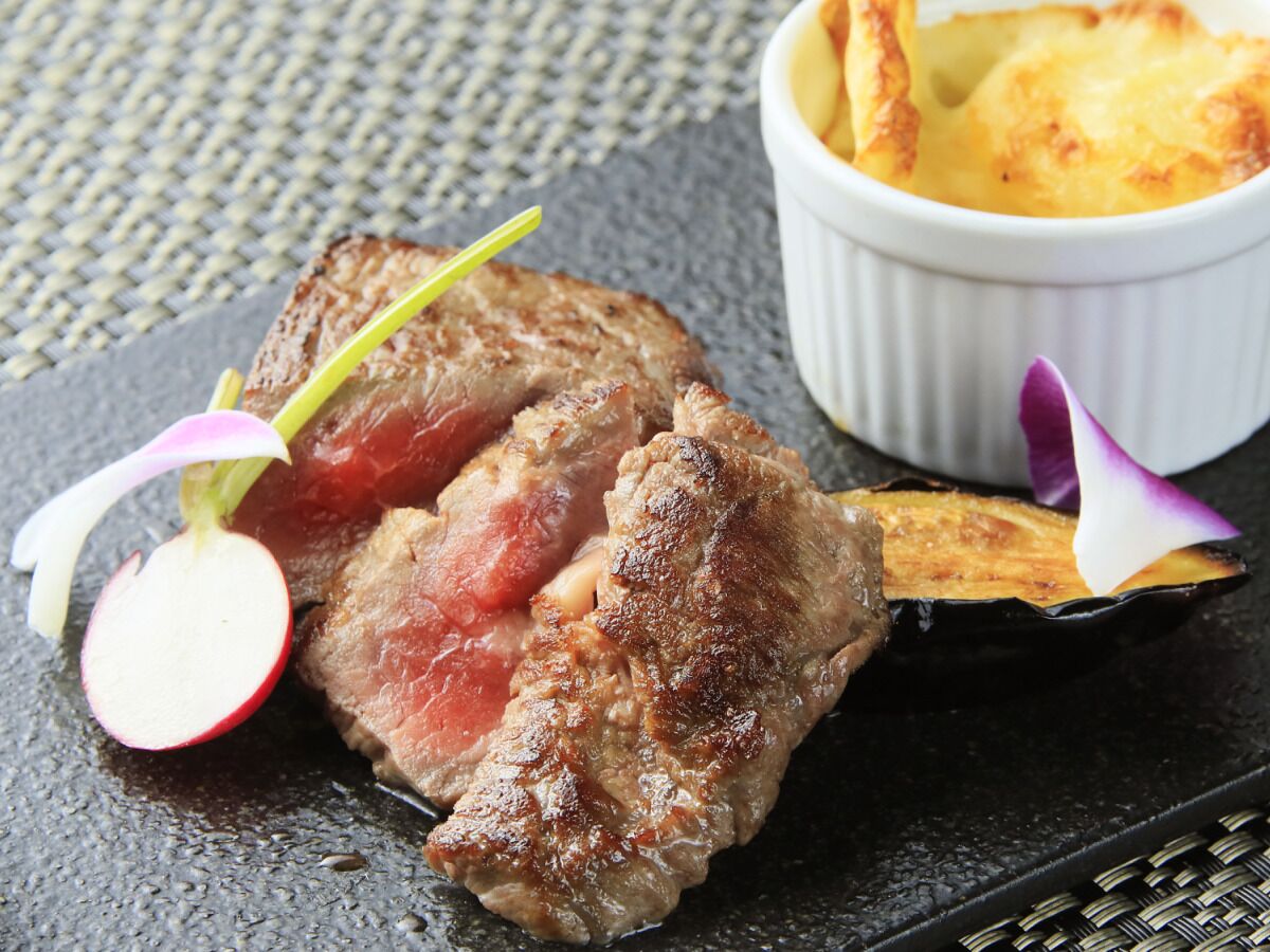 A steak with a garnish of radish and flower, served with a side of fries.
