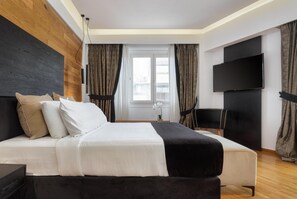 Une chambre d’hôtel moderne dotée d’un grand lit, d’une télévision à écran plat et offrant une vue sur la ville par la fenêtre.