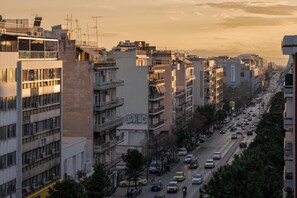 Une vue urbaine avec des immeubles à plusieurs étages, une rue animée et un ciel au coucher du soleil.
