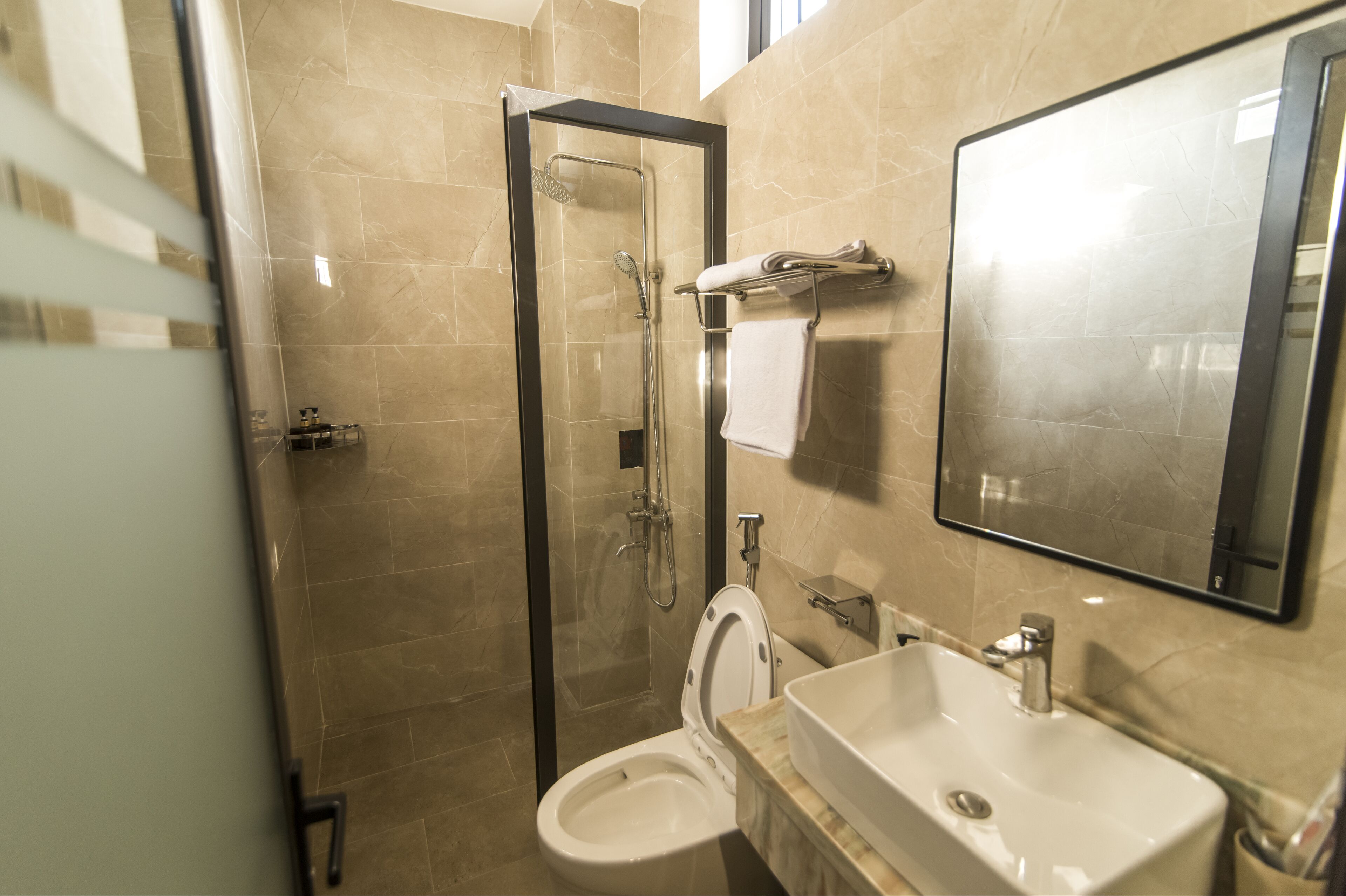 Een moderne badkamer met een glazen douchecabine, een toilet en een wastafel.