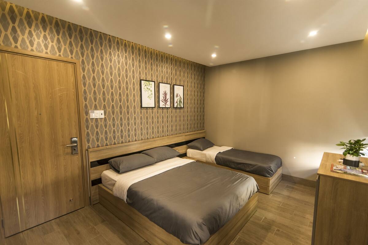 Un dormitorio con dos camas, un armario de madera y un escritorio con una planta.