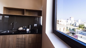 Una cocina moderna con armarios de madera, encimera negra y ventana con vistas a un paisaje urbano.