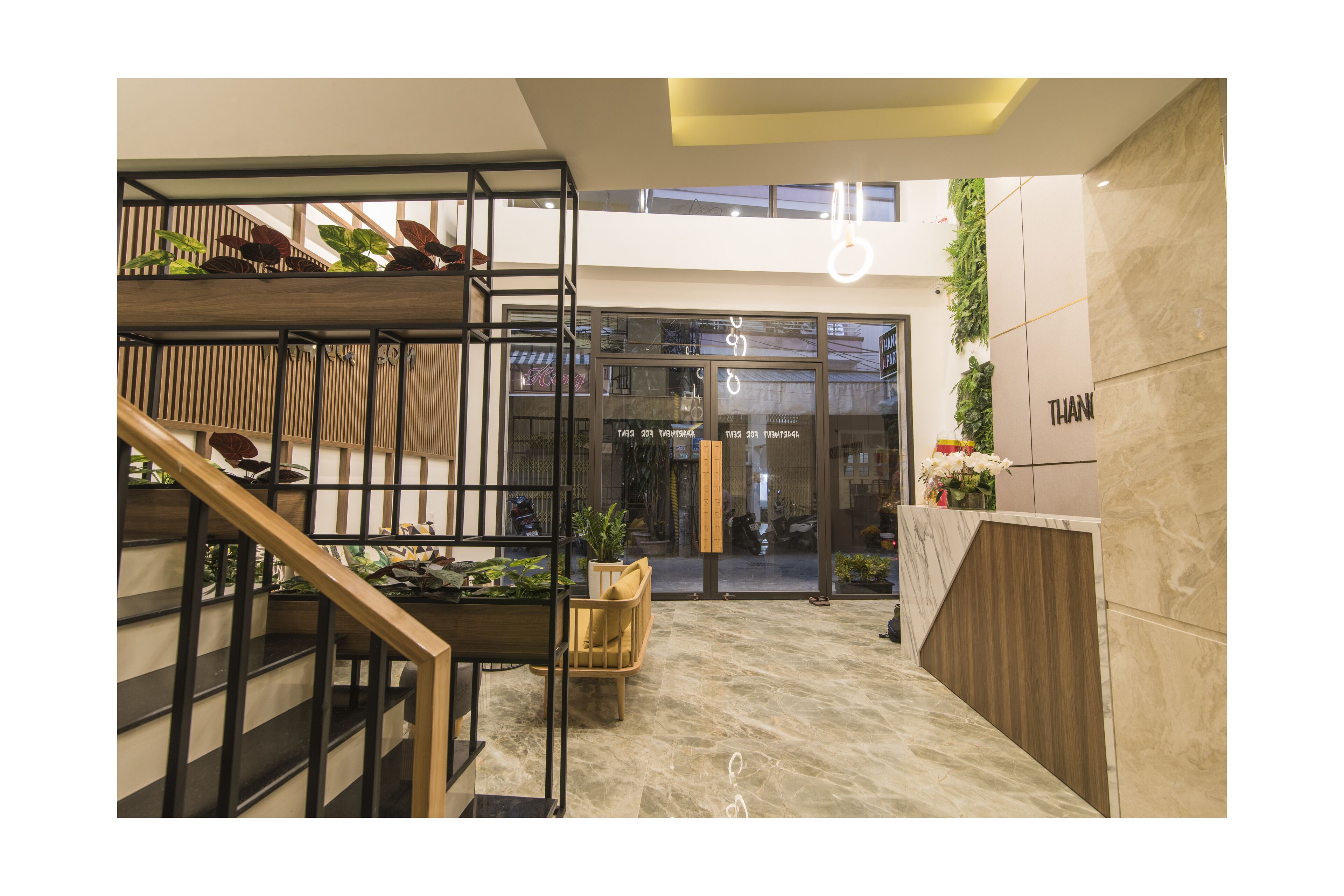 A modern interior with a wooden staircase, a seating area, and a reception desk.