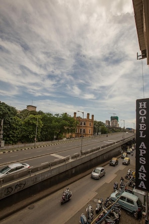 A multi-level highway with vehicles and motorcycles, a building with a sign reading "HOTEL APSARA," and a partly cloudy sky.