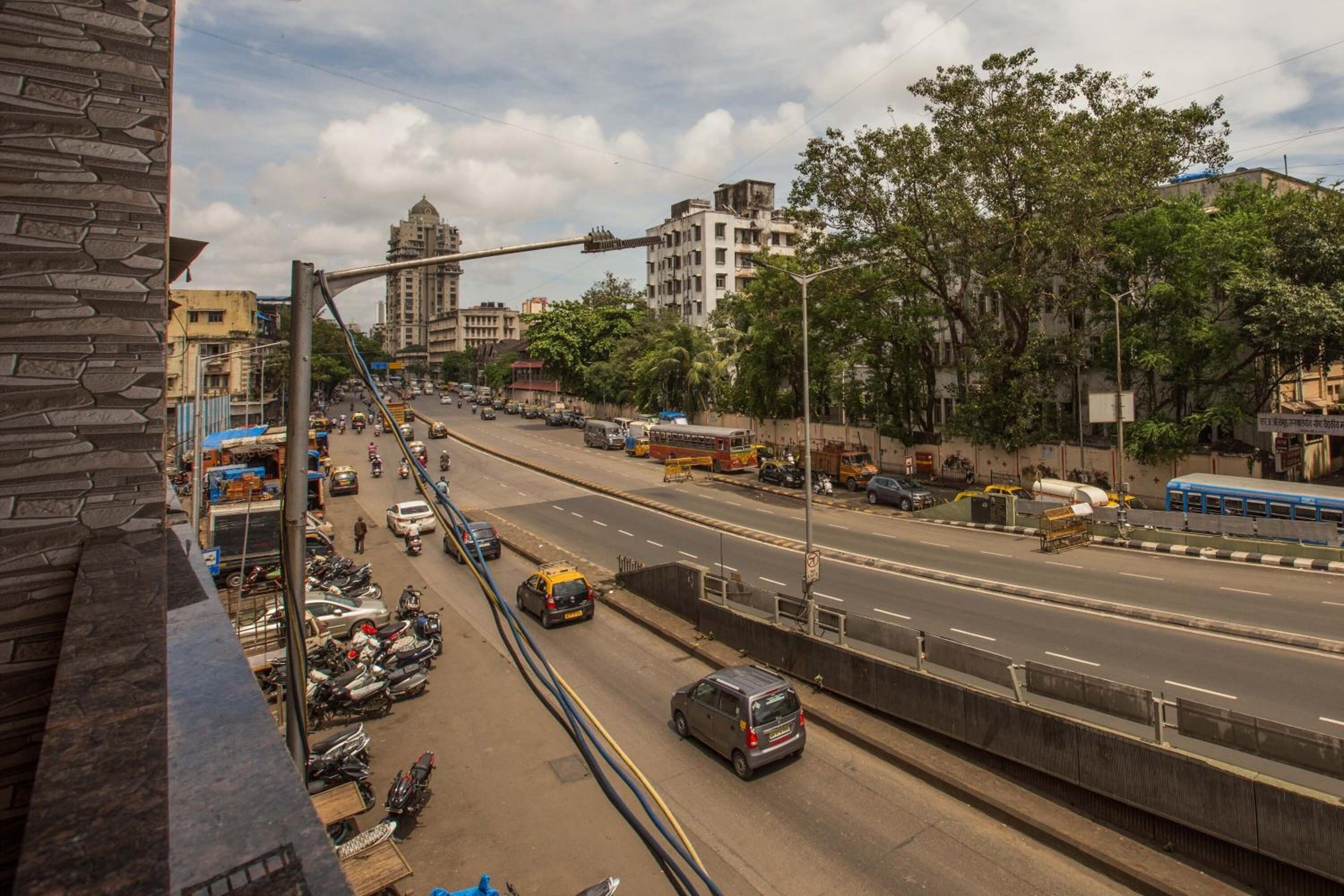 Una avenida urbana con varios carriles, vehículos, un autobús azul y un taxi amarillo.