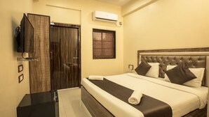 A hotel room with a bed, a television, a window, and an air conditioning unit. - Hotel Apsara Near JJ Hospital (Mumbai)