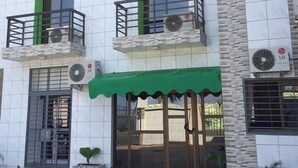 A multi-story building with balconies, air conditioning units, and a green awning over the entrance. - Hotel Samaki Plage (Kribi)