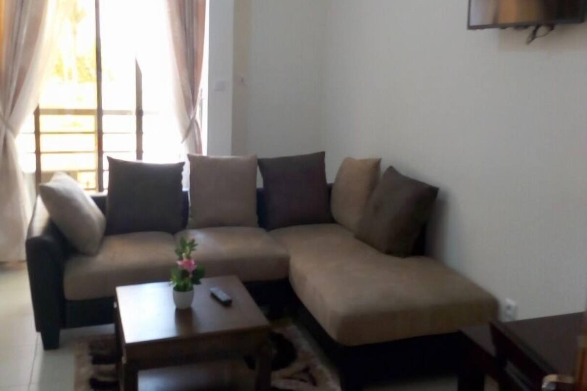 A living room with a sofa, a coffee table, and a TV mounted on the wall.