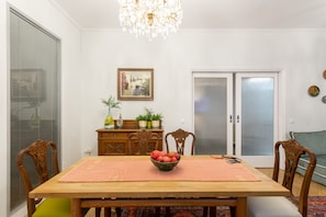Comedor con mesa de madera, sillas, candelabro, un cuadro enmarcado y puerta corredera de vidrio.