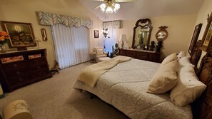 A bedroom with a large bed, a dresser, a chair, and a vanity with a mirror.