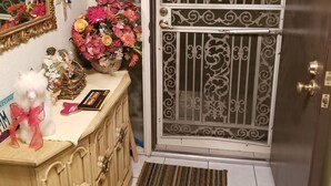 Un pasillo con un armario de madera, un espejo, un osito de peluche y una puerta con barrotes decorativos.
