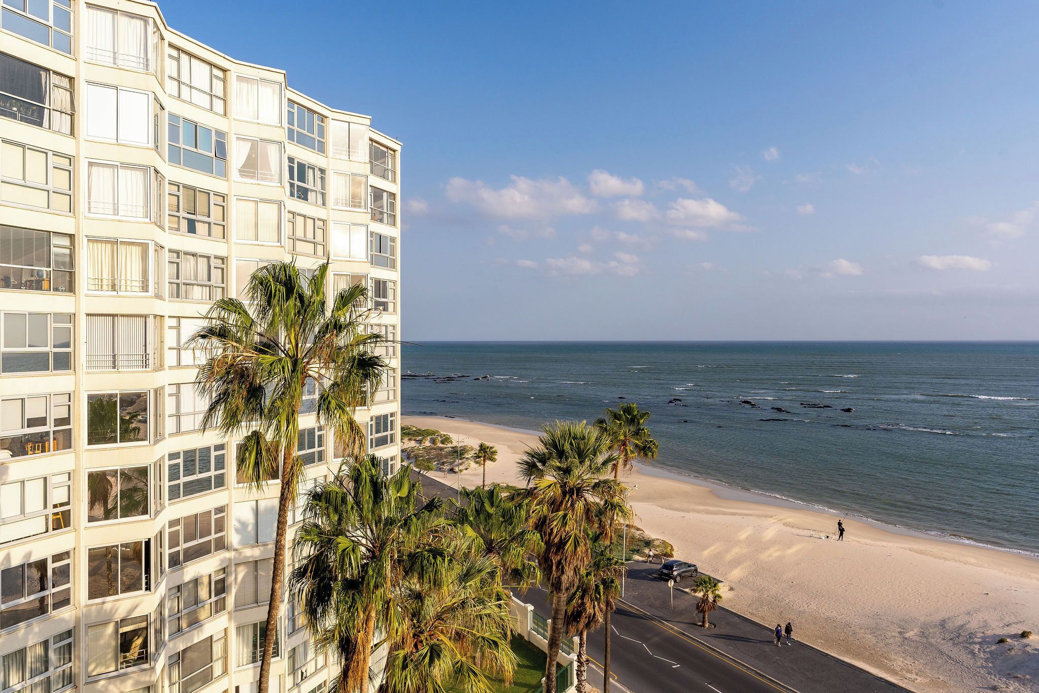 Un hôtel situé en bord de mer, offrant une vue sur l’océan et les palmiers.