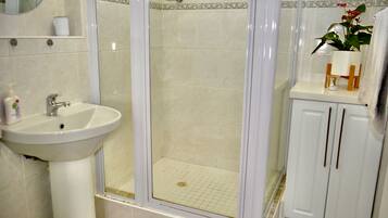 Un baño con lavabo, espejo, cabina de ducha y armarios.