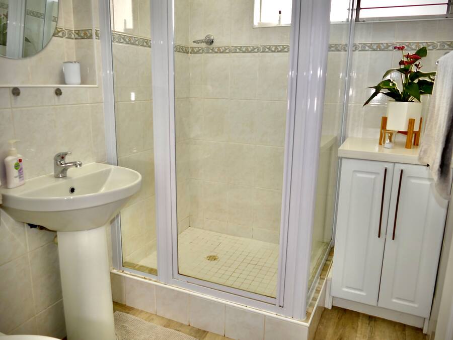 Un baño con lavabo, espejo, cabina de ducha y armarios.