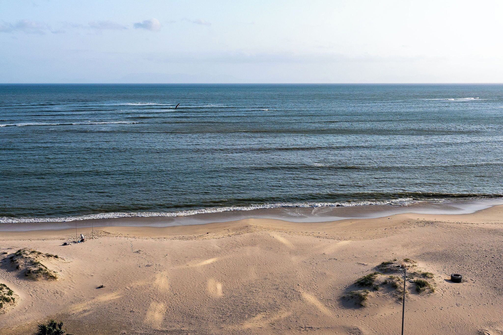 A beach with gentle waves and a clear sky.