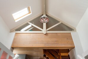 A loft-style room with exposed wooden beams, a sloped ceiling, and a skylight.