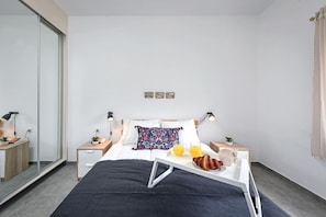 Une chambre dâhĂŽtel moderne Ă©quipĂ©e dâun lit, de tables de chevet, dâune lampe de chevet, dâun plateau de petit-dĂ©jeuner et dâun miroir.
