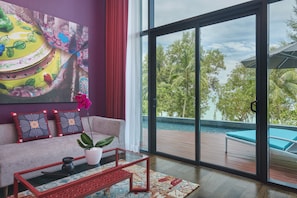 Un salon moderne doté d’une grande fenêtre, d’un canapé, d’une table basse et offrant une vue sur une piscine et un espace verdoyant.
