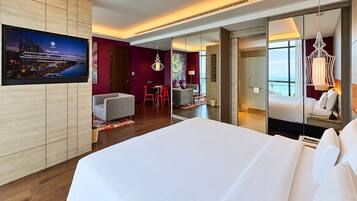 A modern hotel room with a large bed, a television mounted on the wall, and a view of the cityscape through the window.