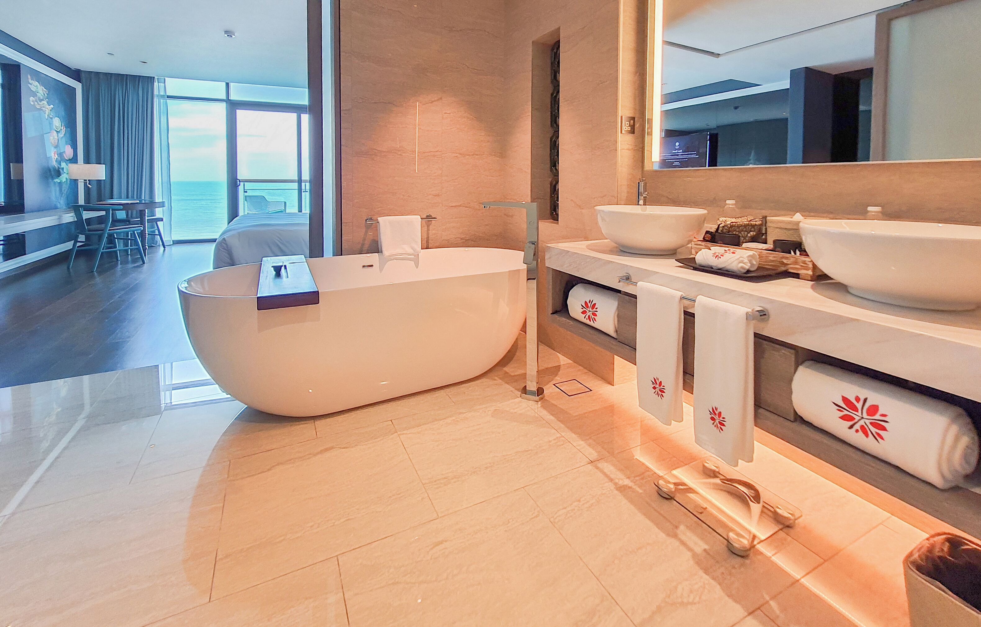 Une salle de bain d’hôtel moderne, dotée d’une grande baignoire, de deux lavabos et d’un grand miroir.